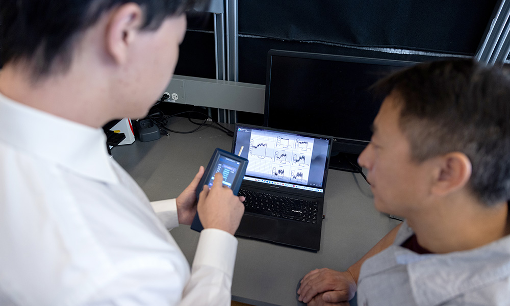 A close-up photo of the backs of the heads of two men who are looking at a computer screen.