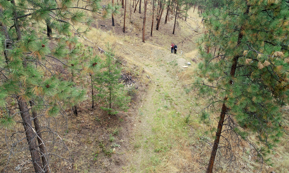 A drone photograph of a deflection berm, with two people standing on top of it to showcase how large it is.