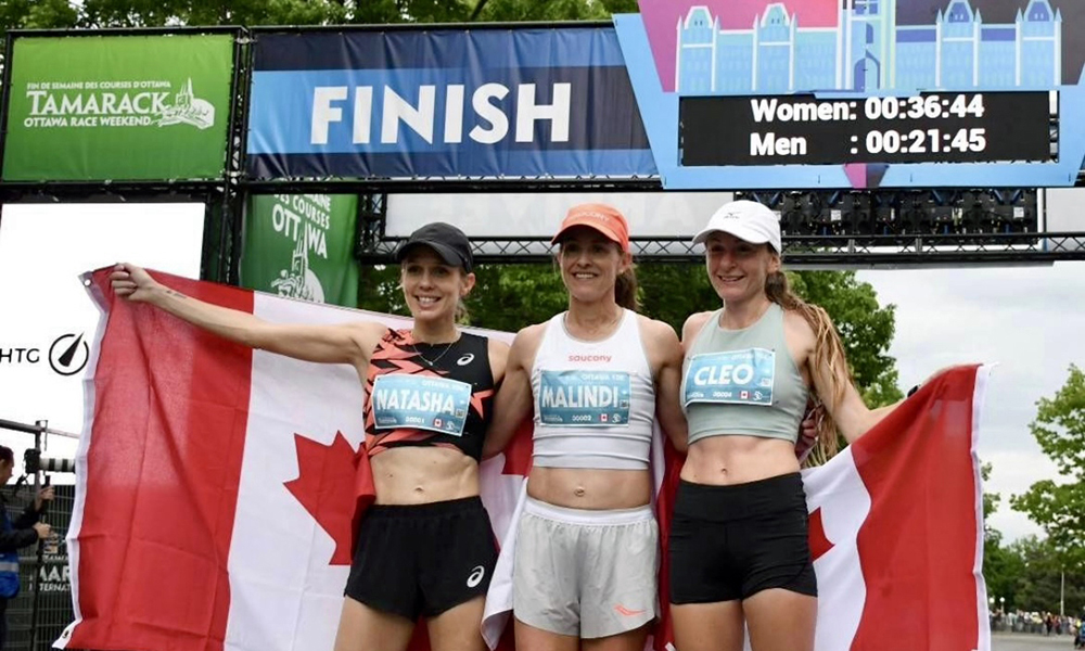 Three women racers stand on the podium after a 10km race.