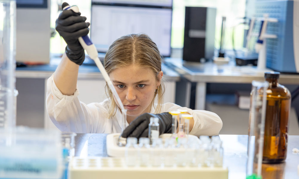 A close-up of Brooklyn using a pipette to place a small amount of liquid into a tiny test tube.