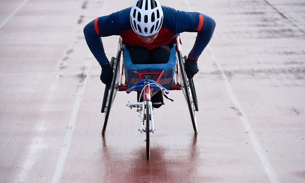 Picture of a wheelchair athlete training while racing in sport wheelchair on an outdoor track.