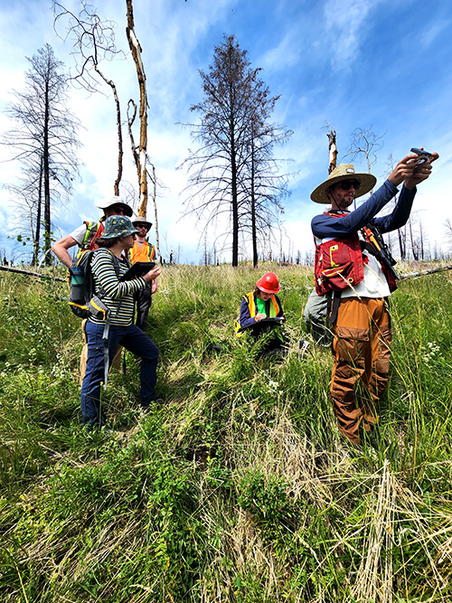 People stand in a field holding various tools to take measurements