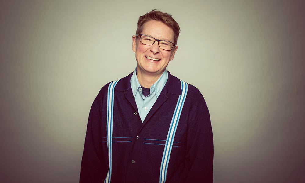 A woman wearing a striped sweater poses for a photo and laughs