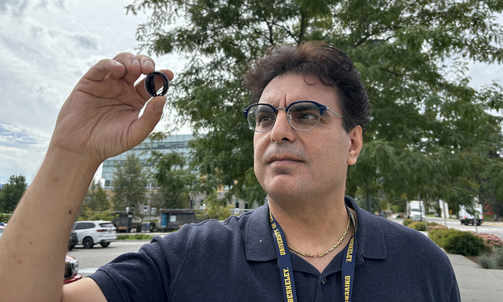 A man holds up a small disc which is actually a manufactured heart valve