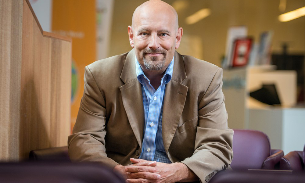 Photo of a researcher sitting on a step and leaning forward in a friendly manner