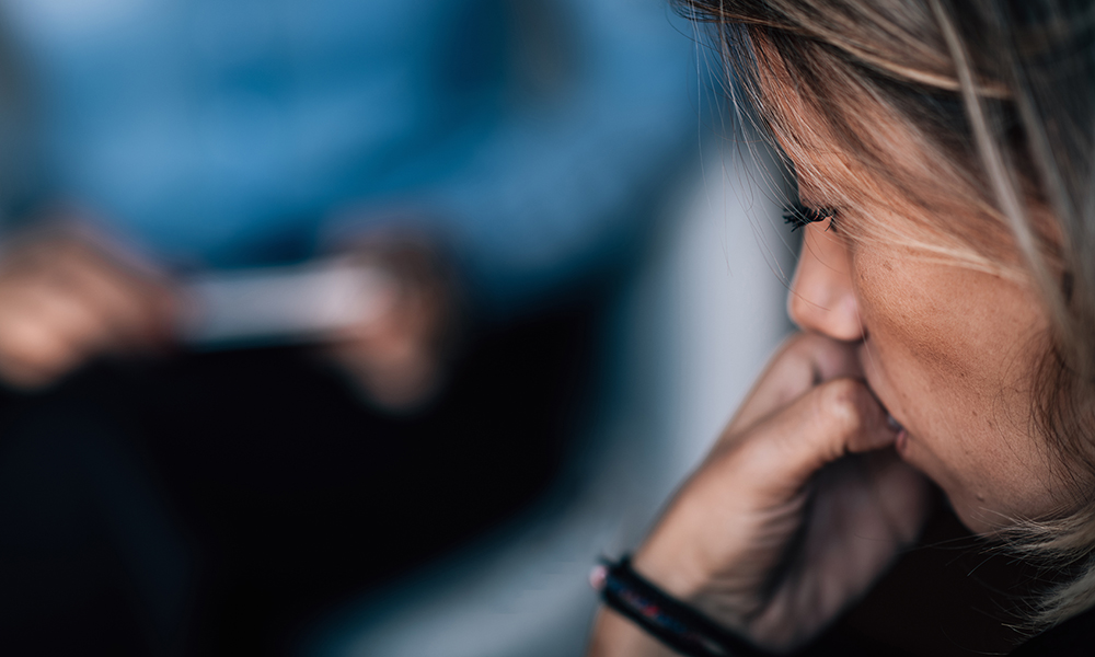 A woman reflects during a cognitive behavioural therapy session with a counsellor.